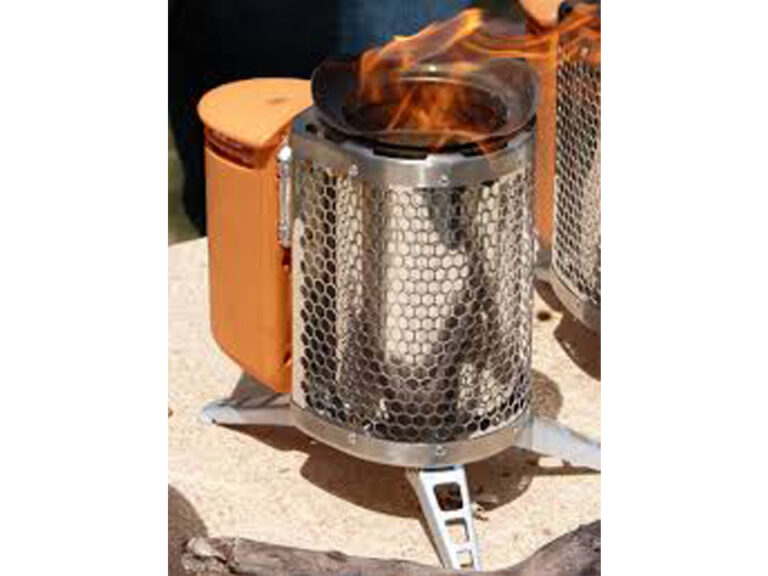 Photo of a small camp stove. An aluminum cylinder with a mesh outer layer and three visible aluminum feet. On the backside is a half cylinder wooden container with lid.  The stove has a black collar coming from the middle section as well as flame.