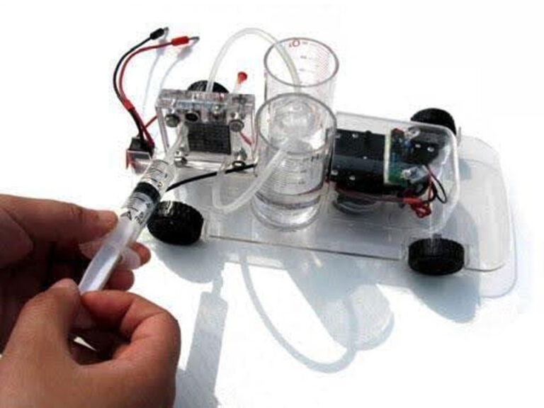 A model car that uses hydrogen electrolysis. On the base there is a small motor, 2 small clear plastic beakers with measurement lines with tubes connecting to the top and bottom of the hydrolysis chamber.  A syringe adds fluid to the chamber.