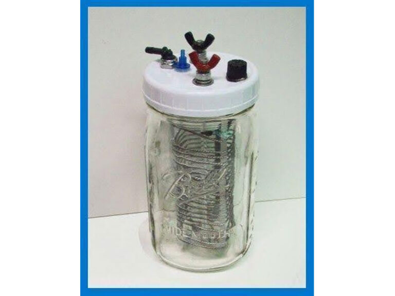 A hydrogen fuel cell made using a mason jar. The lid switch next to a vent and a positive and negative electrical pole with a red and black wingnut respectively. Inside the jar a coil of thick metal wire can be seen.