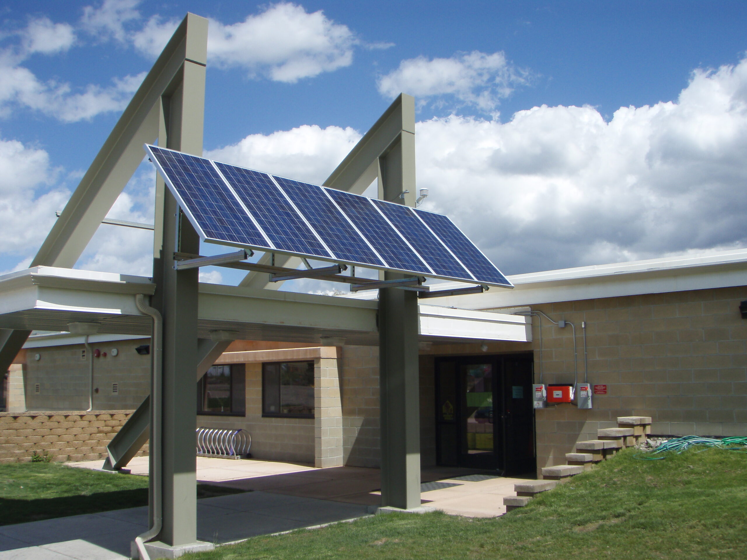 Solar panels mounted next to an awning at the entrance of a building.