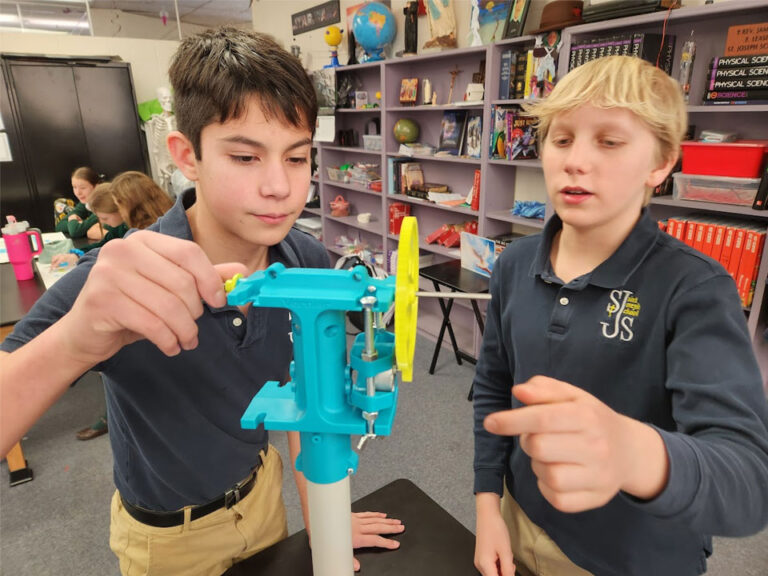 Two boys adjust the turbine hub on a Kidwind wind turbine model