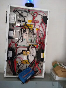 An electrical box with lots of wiring, several strips of lights and a battery hanging out the front. The box has a blue osculating light on top. 